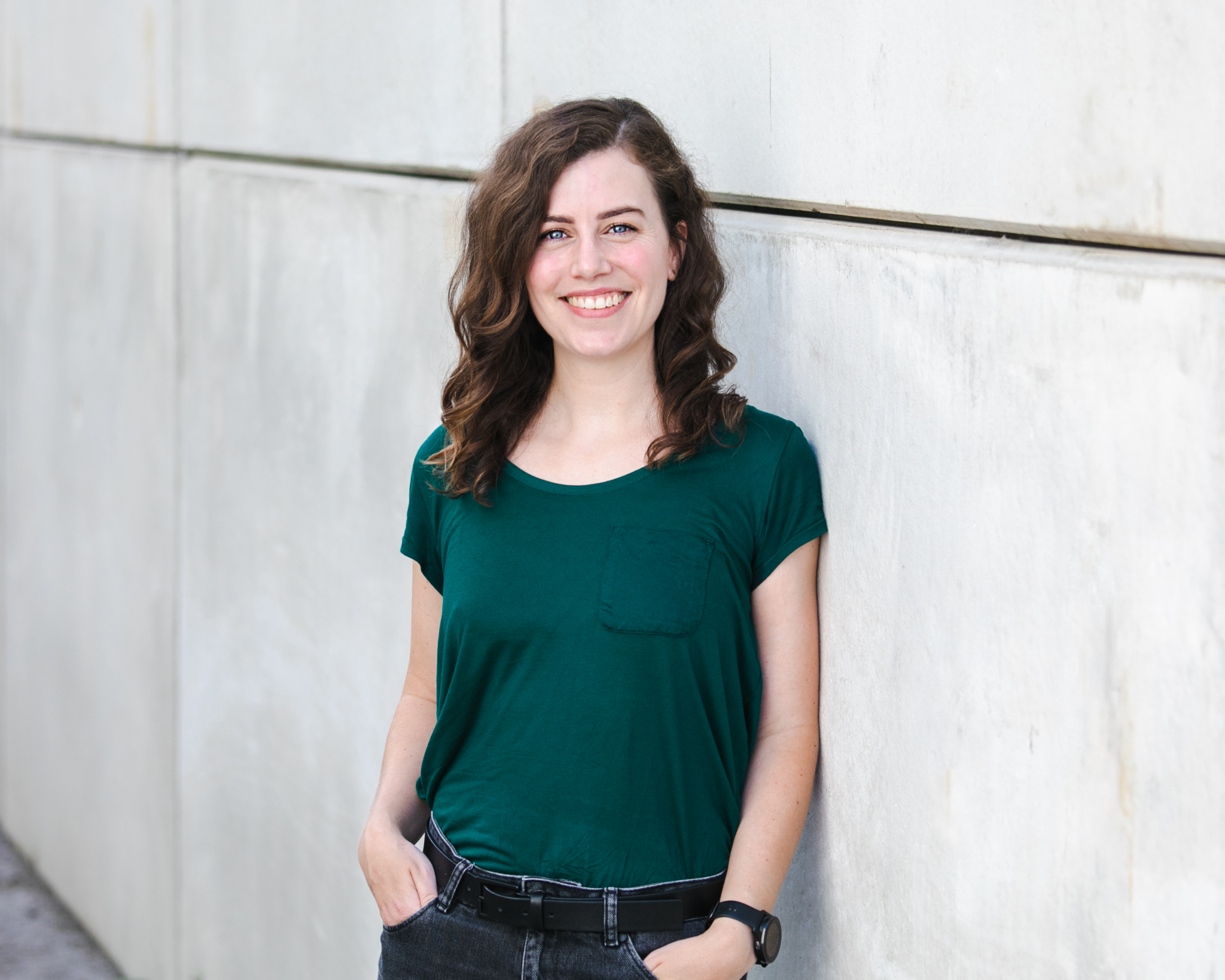 Stefanie Dippelreiter, Grafikdesignerin und Markenexpertin, steht vor einer modernen Betonwand und lächelt – Impact with Love · Brand Design Wien